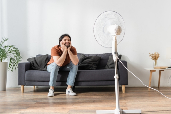 man enjoying standalone fan to boost air conditioner efficiency