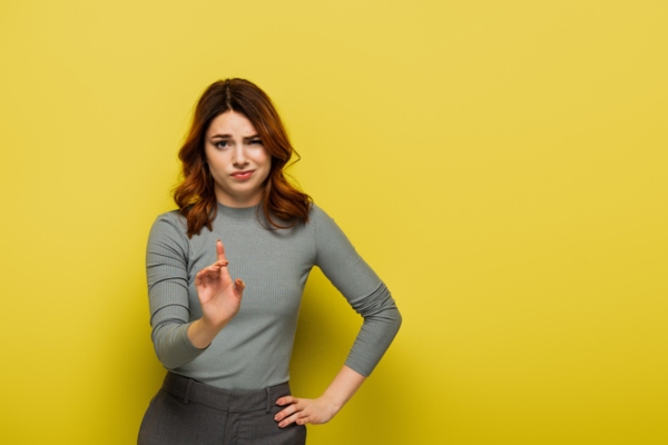 Displeased woman against yellow background standing with hand on hip depicting void of warranty