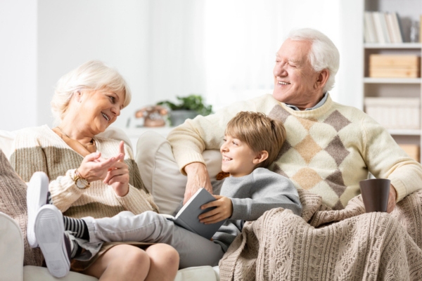 Grandmother and grandfather sitting on couch with their grandson, all wearing sweaters depicting personalized comfort & efficiency