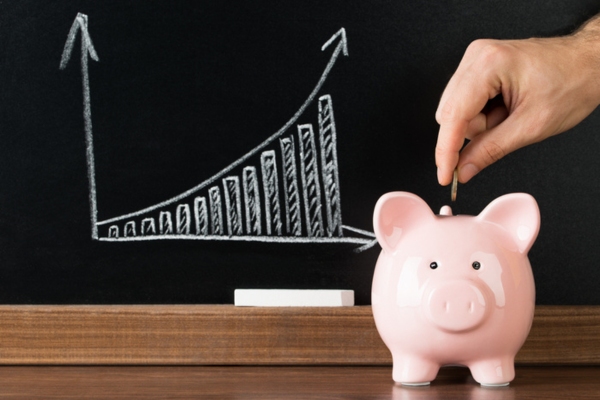 Hand Putting Coin Into Piggy Bank depicting savings