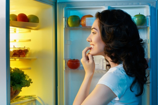 hungry girl looking for fresh food in the fridge during power interruption 