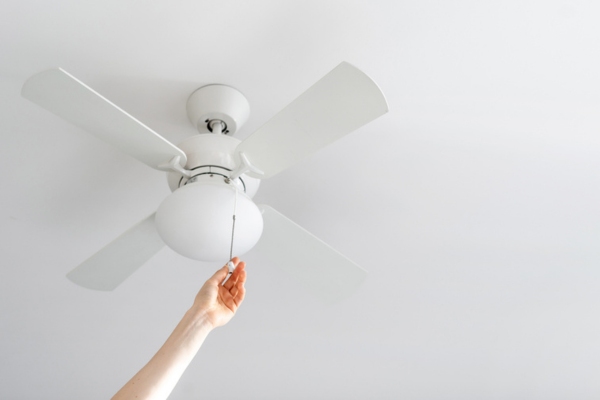 cropped view of a hand changing ceiling fan direction to keep warm in winter