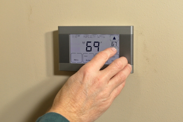 homeowner adjusting programmable thermostat