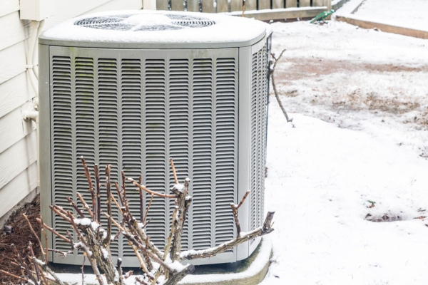 residential heat pump beside dead branches in winter