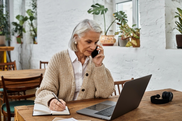 woman looking at computer while on the phone depicting will-call oil delivery