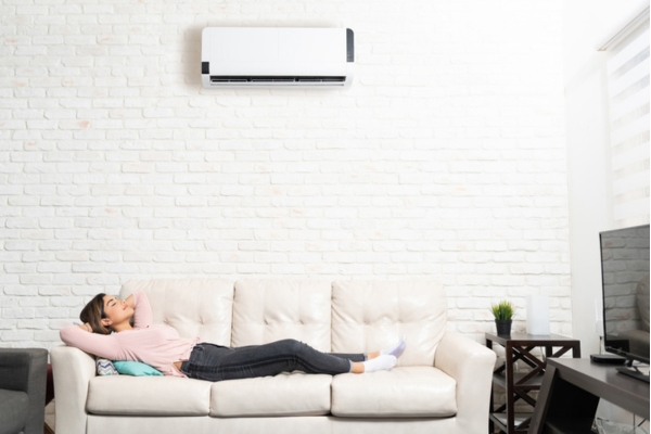 woman taking a nap on the couch with a ductless mini-split heating system