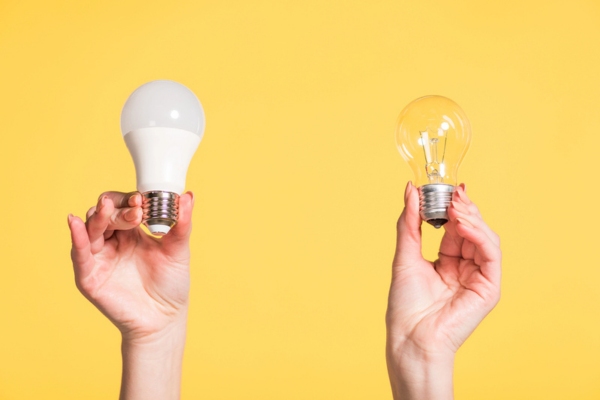 Cropped view of female hands choosing between led and fluorescent bulb depicting energy saving tips