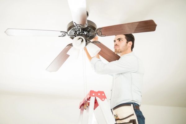 Man in ladder fixing ceiling fan